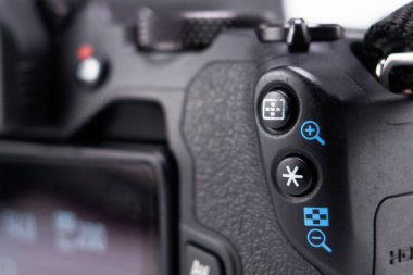 Siyah bir DSLR kamera gövdesinin detaylı görüntüsü, desenli tutuşu, düğmeleri ve kontrolleri vurguluyor. Seçici odak, kameraların özelliklerini vurgular.