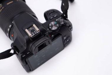 Beyaz arka planda siyah bir DSLR kameranın yukarıdan aşağı görüntüsü. Kamera gövdesi, mercek ve kayışa odaklan..