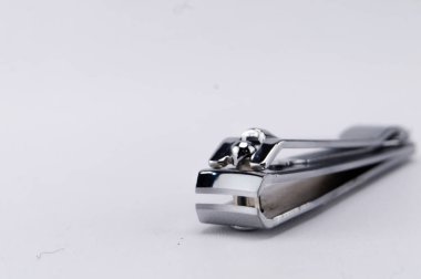 Temiz beyaz arka planda dinlenen gümüş bir tırnak makasının yakın plan görüntüsü tasarımı ve işlevselliğini gösteriyor..