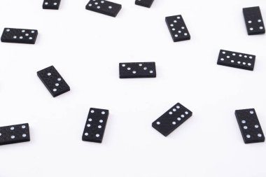 Beyaz çekirdekli siyah domino taşlarından oluşan bir koleksiyon düz beyaz bir arkaplan boyunca dağılır ve basit ve temiz bir kompozisyon oluşturur..