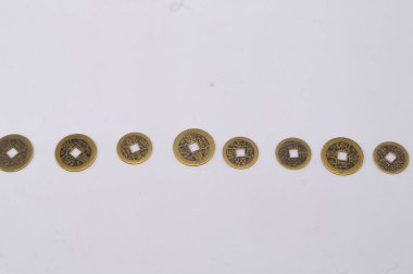 Her birinin merkezinde kare bir delik bulunan sekiz eski Çin sikkesinden oluşan düz bir çizgi, düz beyaz bir arka fona karşı sergileniyordu..