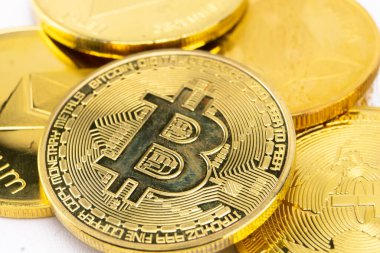 Yakın plan çekimde, kripto para yatırımı konsepti ve finansal teknolojiyi vurgulayan bir yığın altın Bitcoin ve Ethereum sikkesi görülüyor..
