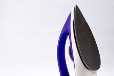 Modern bir ütünün yakın plan çekimi. Ütü mavi ve beyazdır, siyah tabanlı, temiz beyaz arkaplan üzerine kuruludur..