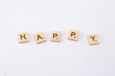 Mutluluk diye hecelenen beş ahşap kiremit, basit ve olumlu bir mesajı iletmek üzere temiz beyaz bir arkaplan üzerinde düzenlenmiştir..