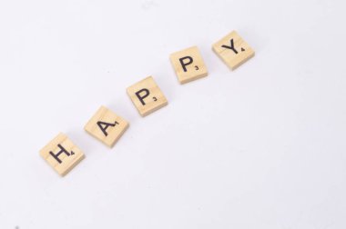 Tahta fayanslar Mutlu yazım beyaz bir yüzey üzerinde çapraz olarak düzenlenir, basit ve pozitif bir mesaj oluşturur.