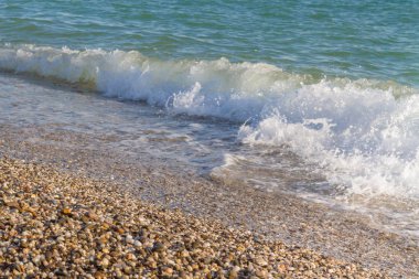 Sandy ve çakıl plaj üzerinde çalışan deniz dalgası
