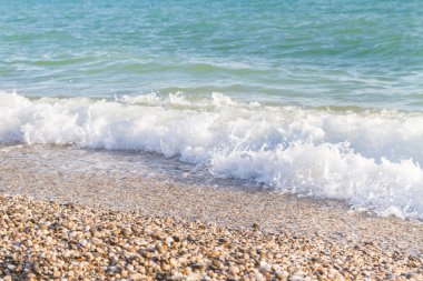 Sandy ve çakıl plaj üzerinde çalışan deniz dalgası
