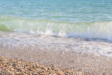 Sandy ve çakıl plaj üzerinde çalışan deniz dalgası