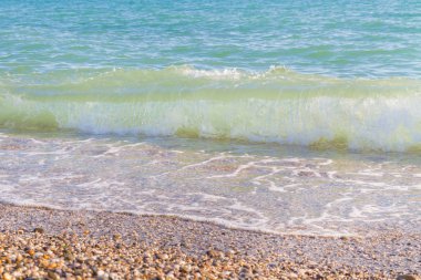 Sandy ve çakıl plaj üzerinde çalışan deniz dalgası