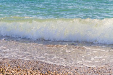 Sandy ve çakıl plaj üzerinde çalışan deniz dalgası