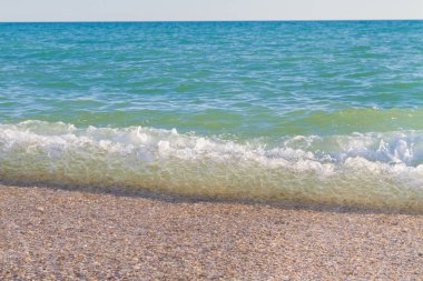 Sandy ve çakıl plaj üzerinde çalışan deniz dalgası