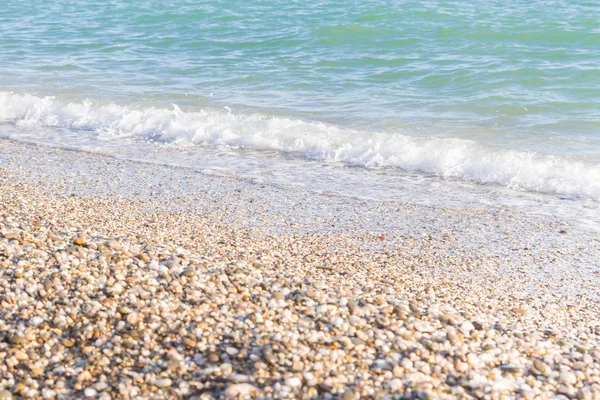 Sandy ve çakıl plaj üzerinde çalışan deniz dalgası