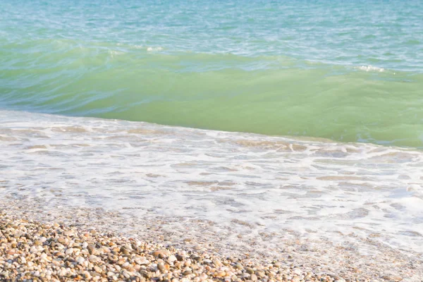 Sandy ve çakıl plaj üzerinde çalışan deniz dalgası