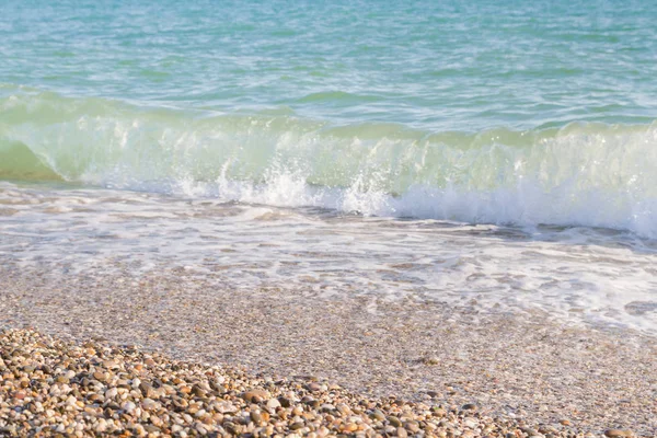 Sandy ve çakıl plaj üzerinde çalışan deniz dalgası