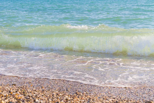 Sandy ve çakıl plaj üzerinde çalışan deniz dalgası