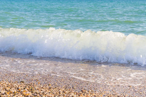 Sandy ve çakıl plaj üzerinde çalışan deniz dalgası
