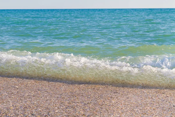 Sandy ve çakıl plaj üzerinde çalışan deniz dalgası