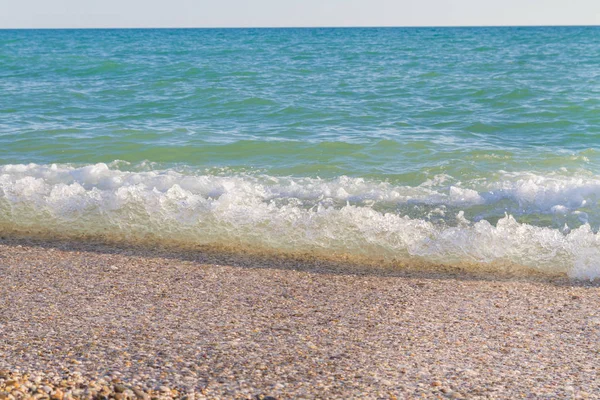 Sandy ve çakıl plaj üzerinde çalışan deniz dalgası