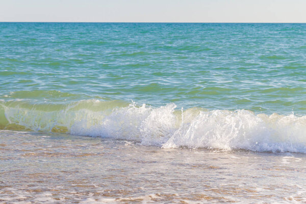 A wave of the sea running on a sandy and pebble beach