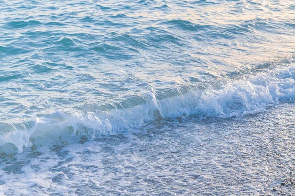 Sandy ve çakıl plaj üzerinde çalışan deniz dalgası