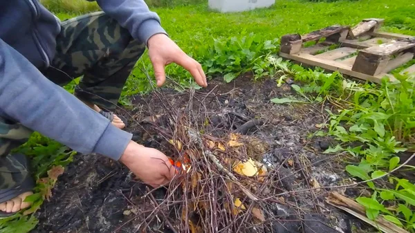 A young man makes a fire of firewood