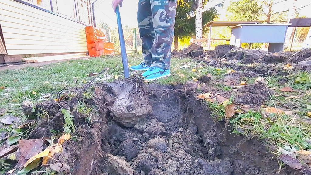 Digging clay in the ground with a shovel in the fall