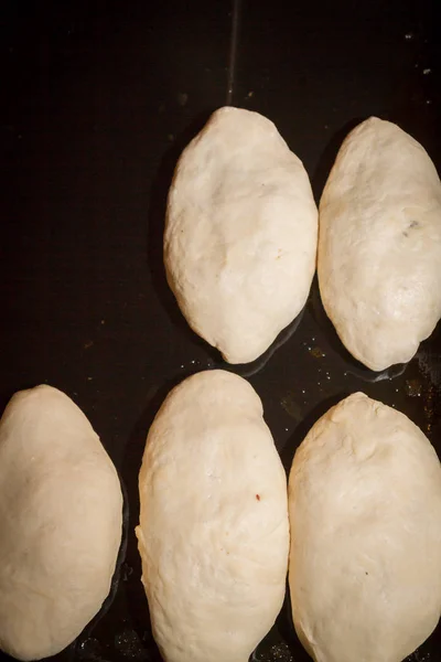 Свежеиспеченные пироги лежат на пекарном листе перед приготовлением — стоковое фото