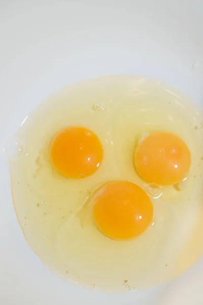 Three broken chicken eggs in a white mixing bowl — Stock Photo, Image