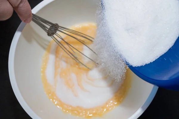 El azúcar se añade al huevo batido para el postre —  Fotos de Stock