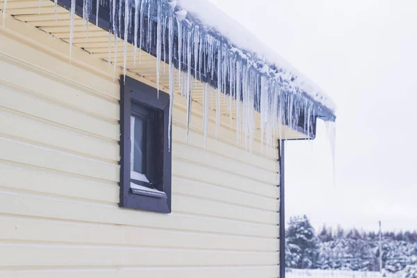 Visí rampouchy ze střechy soukromého domu v zimě — Stock fotografie