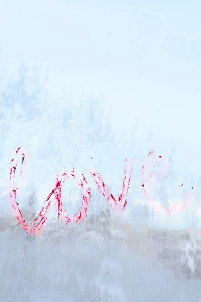 Inskriften älskar skriftliga läppstift på en vinterfrusen fönster — Stockfoto