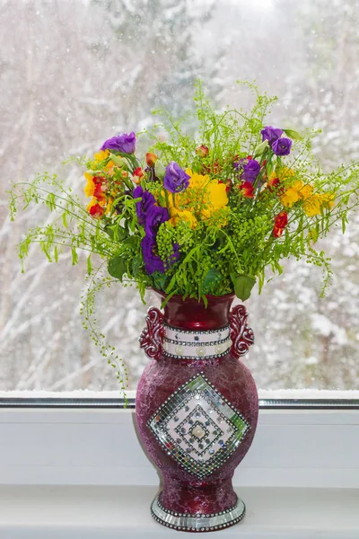 Um vaso bonito de flores de primavera está em uma janela em uma neve — Fotografia de Stock