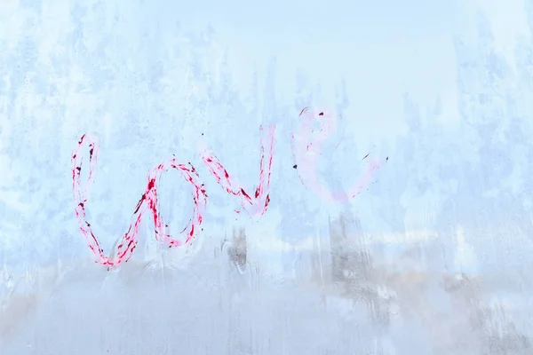 A inscrição amor escrito batom em uma janela de inverno congelado — Fotografia de Stock