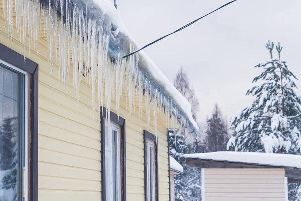 Eiszapfen hängen im Winter vom Dach eines Privathauses — Stockfoto