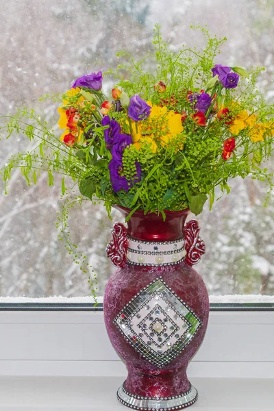 Um vaso bonito de flores de primavera está em uma janela em uma neve — Fotografia de Stock