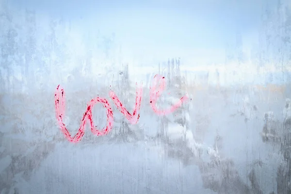 A inscrição amor escrito batom em uma janela de inverno congelado — Fotografia de Stock
