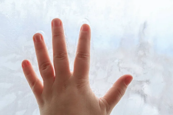 Mão na janela fria de inverno congelada com padrões — Fotografia de Stock