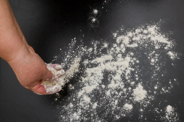 La farina bianca viene versata su un tavolo nero prima di cuocere i biscotti — Foto Stock