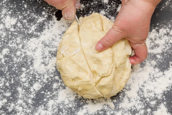 Cutting a large piece of dough on a table with flour for making — Stock Photo, Image
