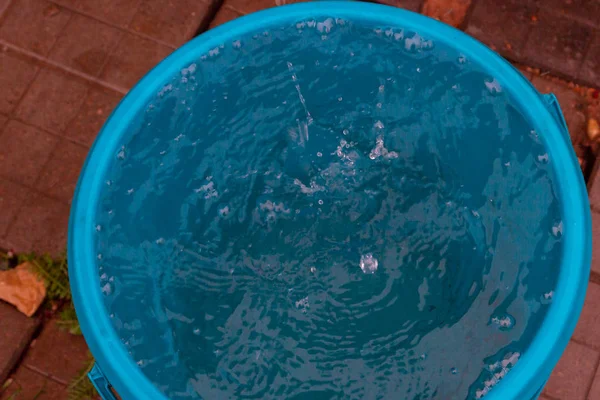 Βροχή στάζει σε ένα μπλε πλαστικό κουβά νερού — Φωτογραφία Αρχείου