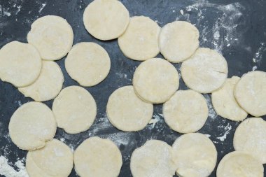 Dağınık bir masada roundels halinde kesilmiş çiğ hamur haddelenmiş