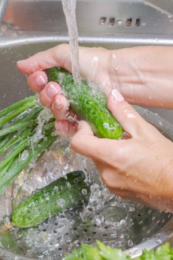 Taze yeşillik musluk genç kadın altında su ile yıkar