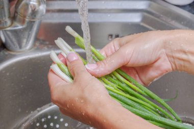 Taze yeşillik musluk genç kadın altında su ile yıkar