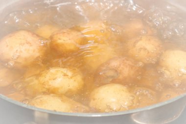 Yeni patatesler derilerinde bir tencerede kaynatın