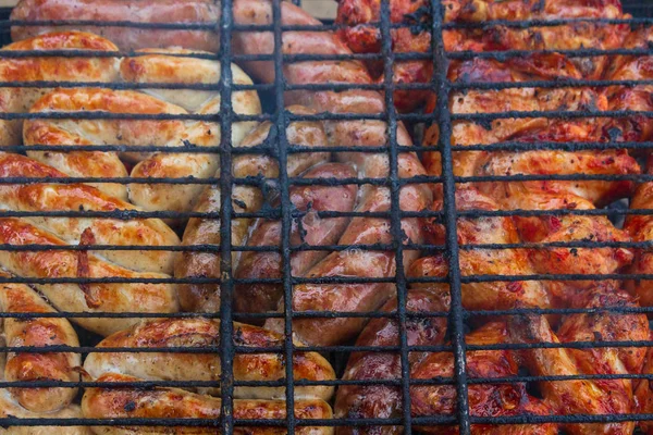 Cozinhar asas de carne grelhadas e salsichas na grelha — Fotografia de Stock