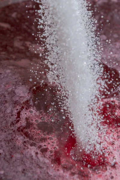 Aggiunta di zucchero allo sciroppo di bacche che viene cotto sul fornello — Foto Stock