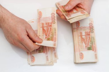 Bir adamın eli beş bin rublelik banknotları sayar ve taşır.