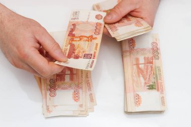 Bir adamın eli beş bin rublelik banknotları sayar ve taşır.