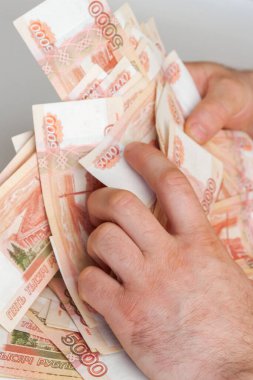 Beş bin rublelik Rus banknotlarıyla erkeklerin elinde büyük miktarda para var.