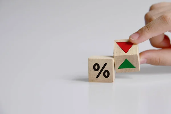 Hand is turning a dice and changes the direction of an arrow symbolizing that the interest rates are going down (or vice versa) 